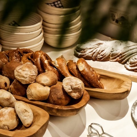 Romantik Hotel Hirschen: Frühstück Verschiedene frische Brote und Gebäck auf Holzschalen und einem weißen Tisch