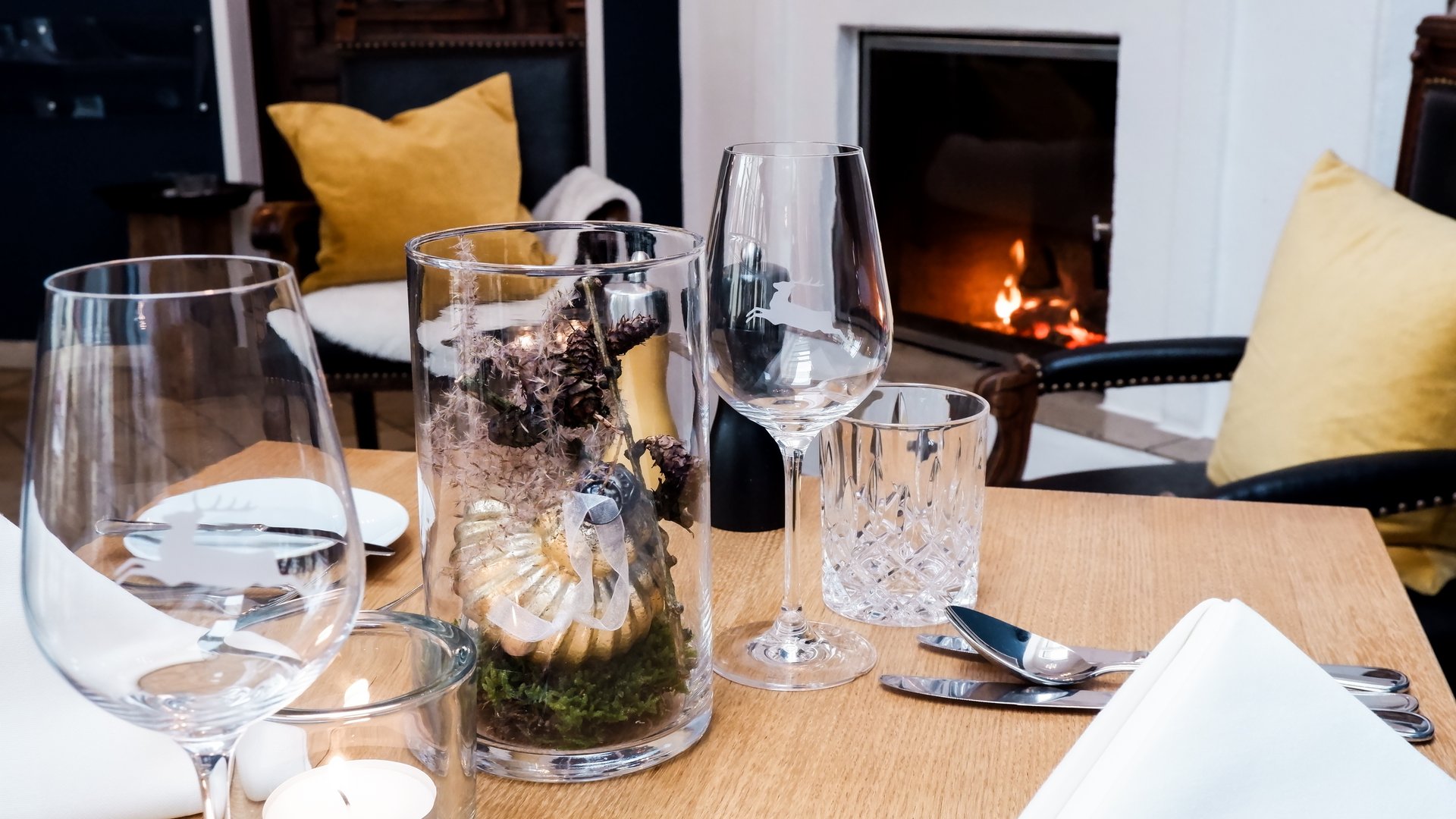 Gasthof Parsberg: Ein Gruß an den guten Geschmack Gemütlich gedeckter Tisch vor Kamin mit Glasdekoration und gelben Kissen