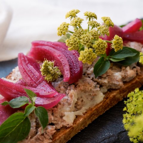 Eco-friendly hotel in Germany with Hirschenmanufaktur Whole grain bread with spread, red onions, green herbs, and yellow flowers