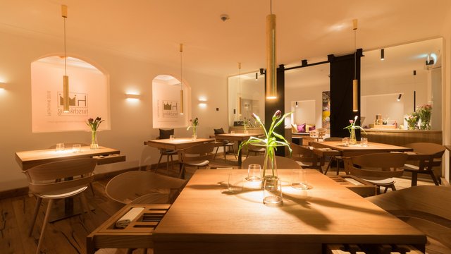 Hirschenblobb: Our bar Cozy modern restaurant interior with wooden tables and flowers under warm lighting