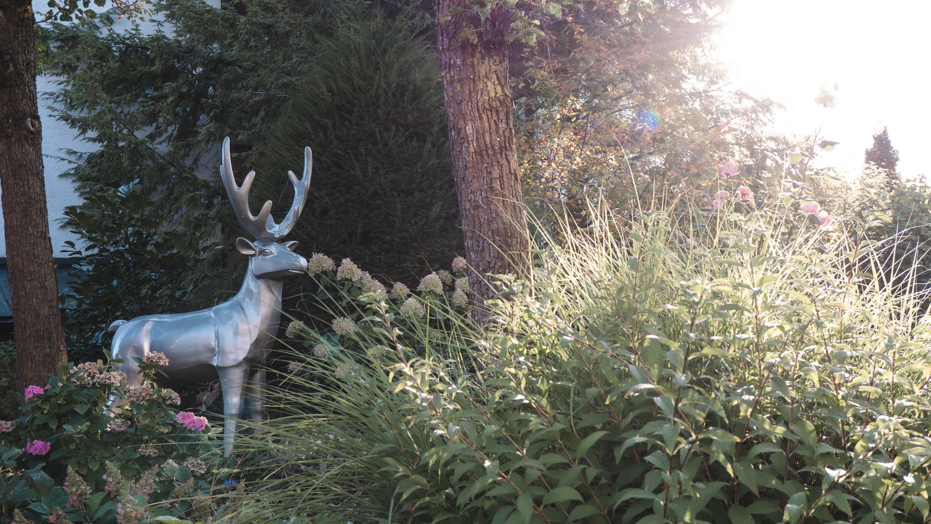 Wellness Oberpfalz – GartenSPA im Romantik Hotel Hirschen Silver metal deer statue in garden among flowers and trees