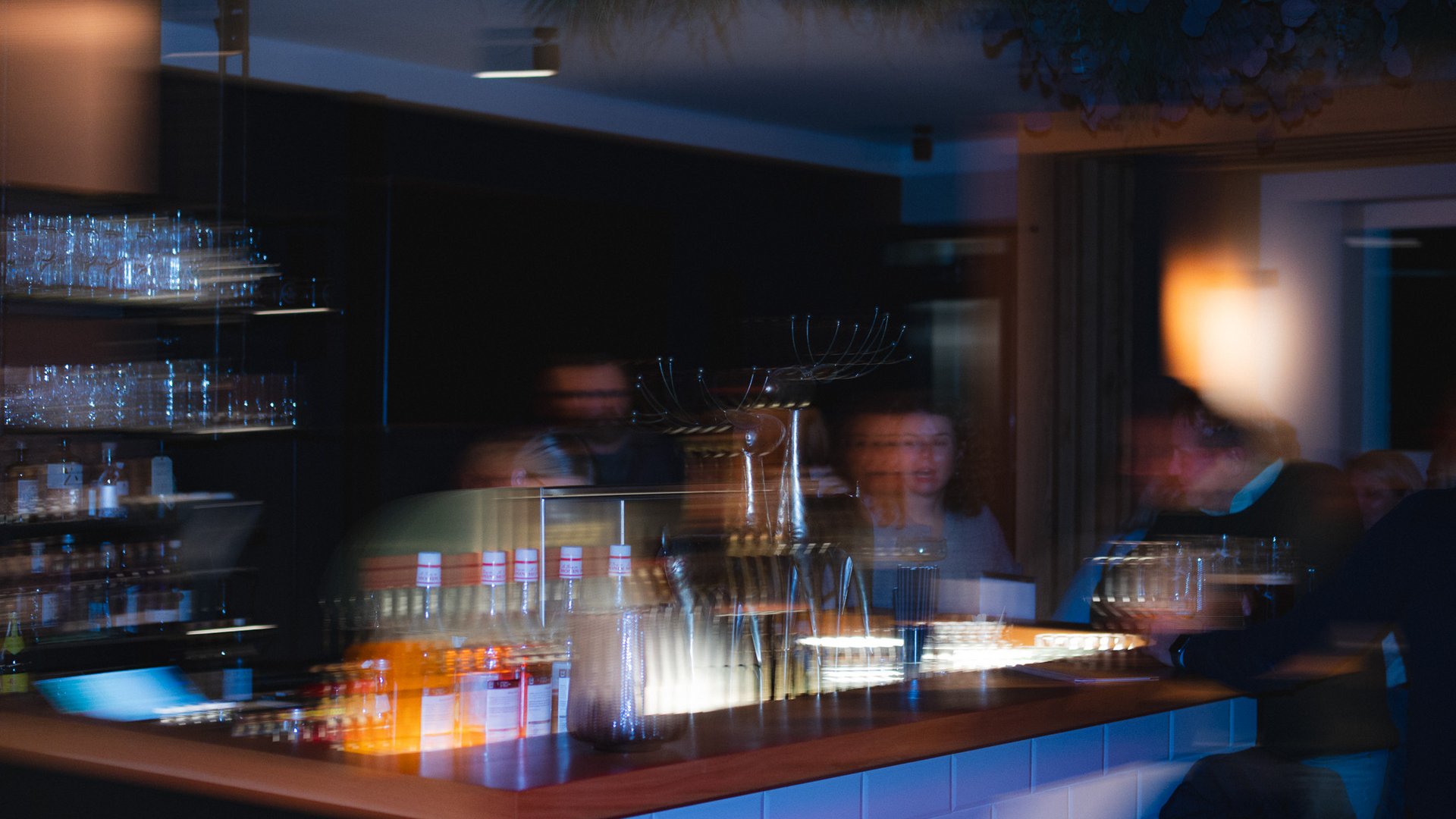 Hirschenblobb: unsere Bar Verschwommene Szene einer Bar mit Menschen und beleuchtetem Tresen