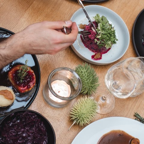 Guesthouse in Parsberg: A salute to great taste Person enjoying a meal with various dishes on a wooden table