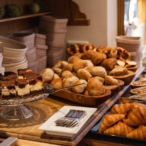 Brunch - das Langschläferfrühstück Buffet mit Croissants, Brötchen, Kuchen und Besteck auf Holztisch