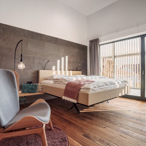 Deine Anfrage im Romantik Hotel Hirschen Modernes Schlafzimmer mit Holzfußboden, Sessel und großen Fenstern