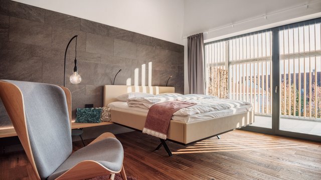 Offers from Romantik Hotel Hirschen Modern bedroom with wooden floor, armchair, and large windows