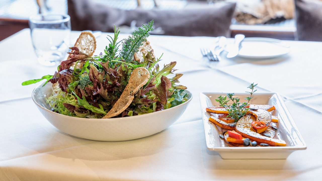 Frischer Salat und gegrilltes Gemüse auf einem gedeckten Tisch