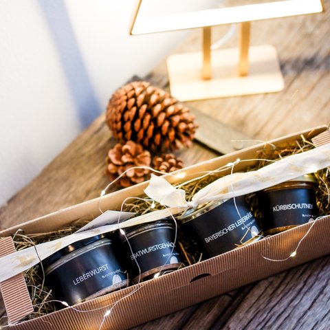 Eco-friendly hotel in Germany with Hirschenmanufaktur Gift box with four cans of spread on wooden table with pinecones and lamp