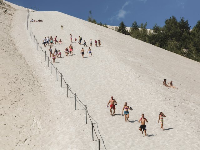 Romantik Hotel Hirschen: Bildergalerie Menschen klettern und laufen auf einer großen Sanddüne bei sonnigem Wetter