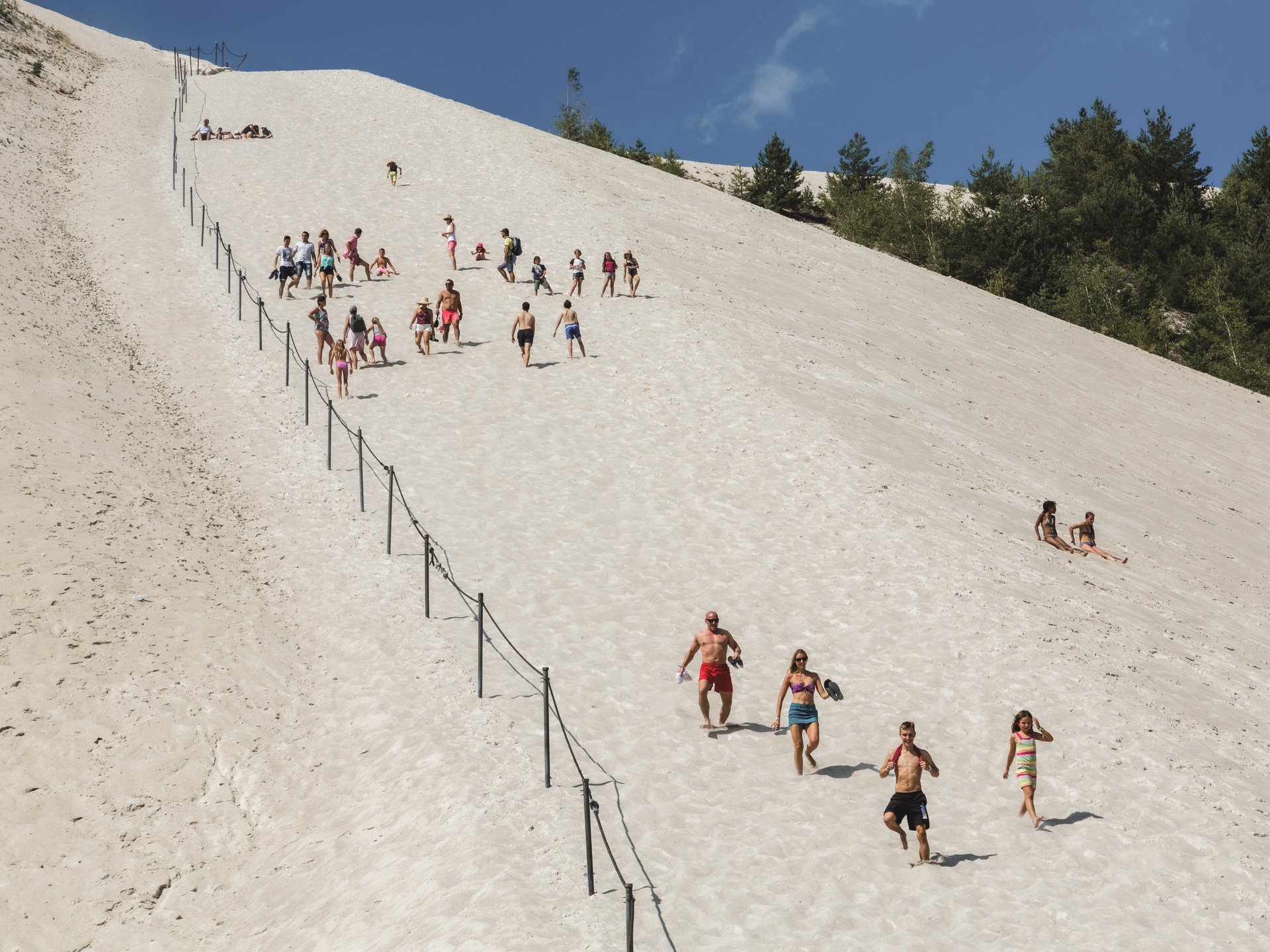 Wandern, Radfahren & Natur erleben Menschen klettern und laufen auf einer großen Sanddüne bei sonnigem Wetter