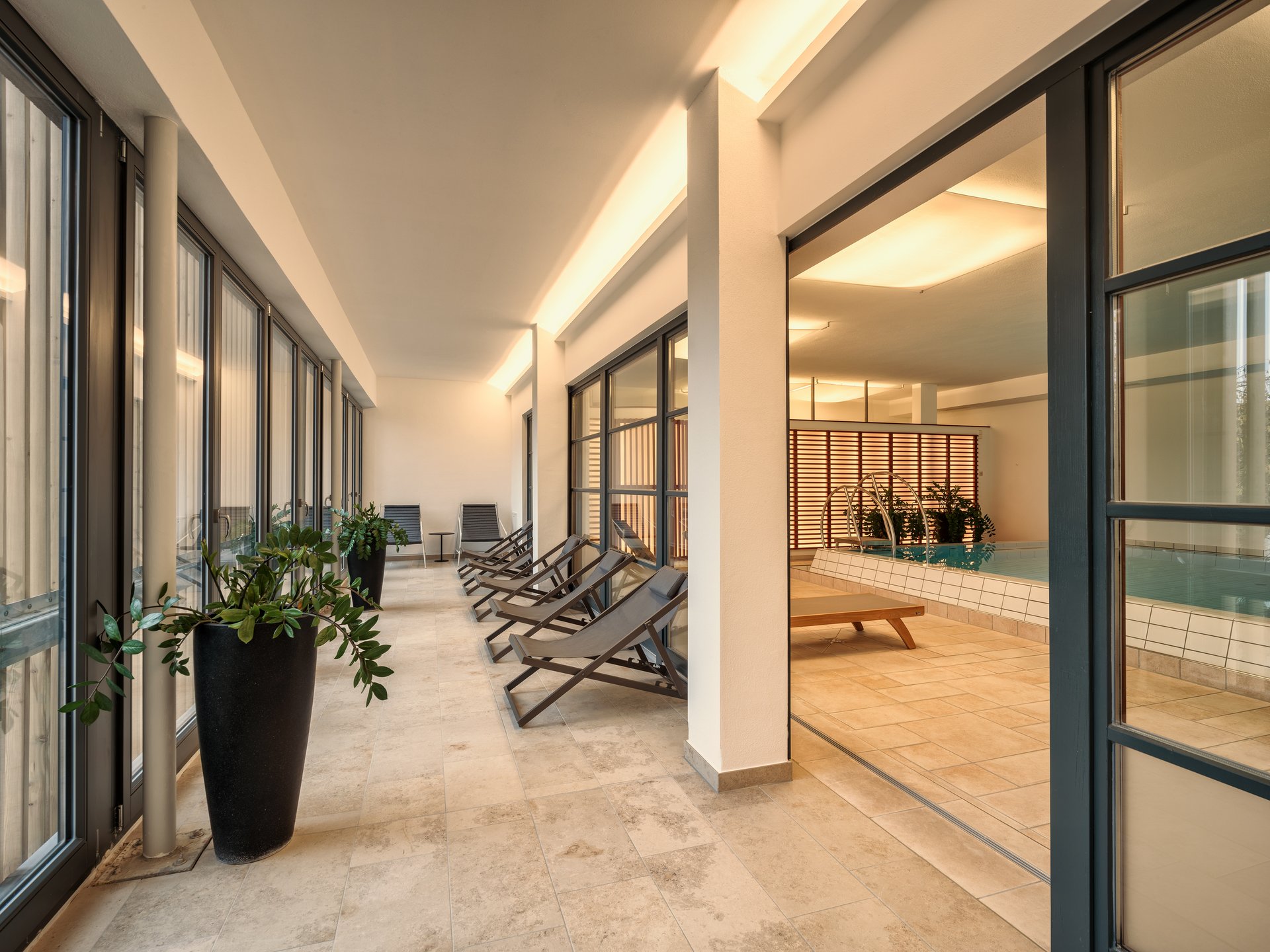 Saunas, Pool & Natural Pool in the Upper Palatinate | Romantik Hotel Hirschen Modern indoor pool with deck chairs and plants in relaxation area