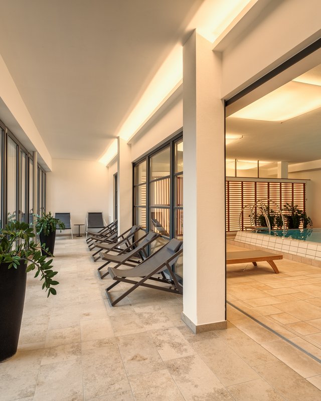 Looking for a hotel with bike rental in Bavaria? Modern indoor pool with deck chairs and plants in relaxation area