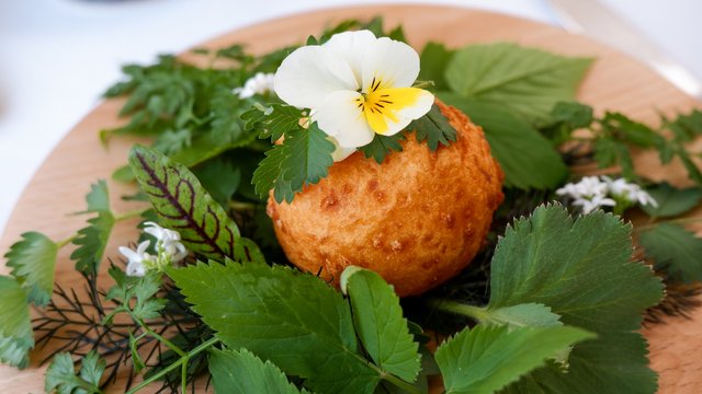 Nachhaltiges Hotel in Bayern mit Hirschenmanufaktur Gebratene Kugel auf Holzplatte mit essbaren Blättern und Blume