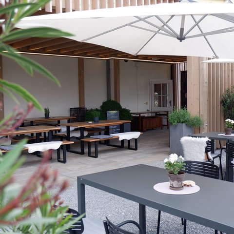 Beer garden in Parsberg: HirschenBlobb Modern outdoor seating area with tables, chairs, and plants under umbrella