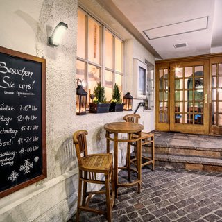 Inclusive services: Everything a stag could want. Restaurant entrance with wooden chairs and table and a board displaying opening hours