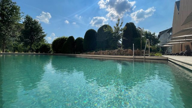 Romantik Hotel Hirschen: Blog Klares Schwimmbad bei sonnigem Himmel mit Bäumen im Hintergrund