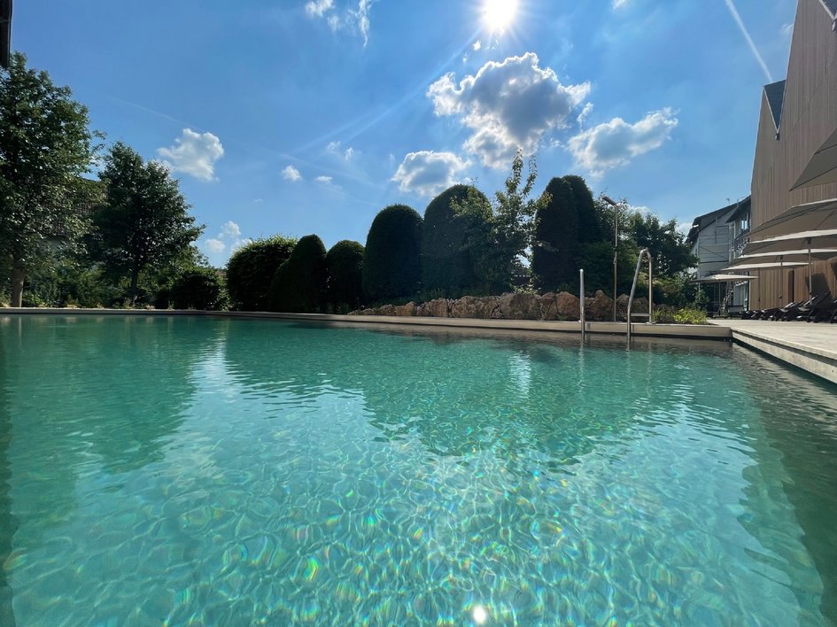 Looking for sustainable hotels in Germany? Clear swimming pool under sunny sky with trees in background