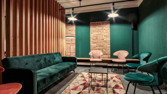 Romantik Hotel Hirschen: Blog Modernes Wohnzimmer mit grünem Sofa, buntem Teppich und rosa Stühlen