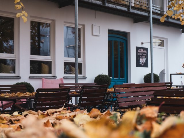 Romantik Hotel Hirschen: Bildergalerie Leere Außensitzplätze eines Cafés mit Herbstlaub auf dem Boden und Tischen