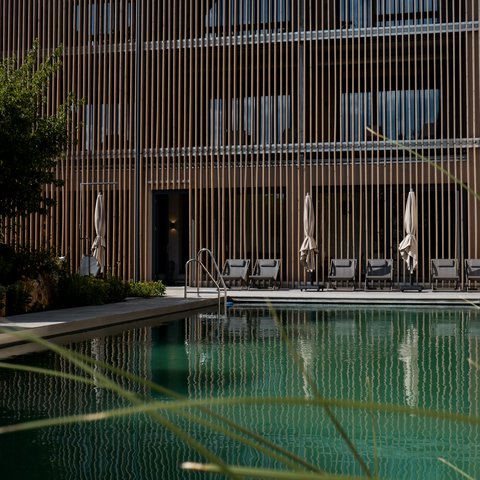 Tageswellness in der Oberpfalz Schwimmbad mit Liegestühlen vor modernem Holzgebäude bei Tageslicht