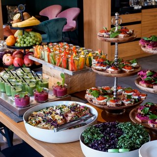 Tagung mit Mehrwert Buffet mit frischem Obst, Gemüsesticks, Dips und belegten Broten auf Holztabletts