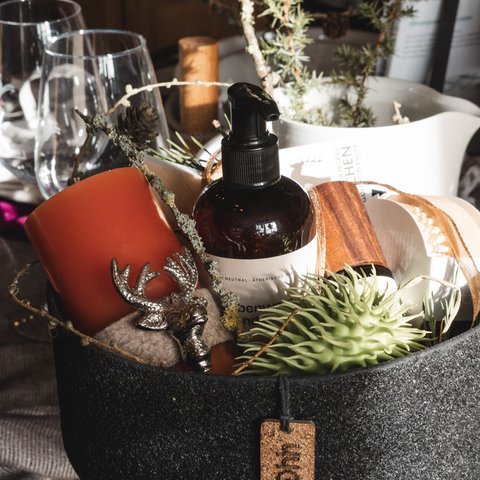 Eco-friendly hotel in Germany with Hirschenmanufaktur Decorative basket with candle, lotion bottle, and plants on wooden table