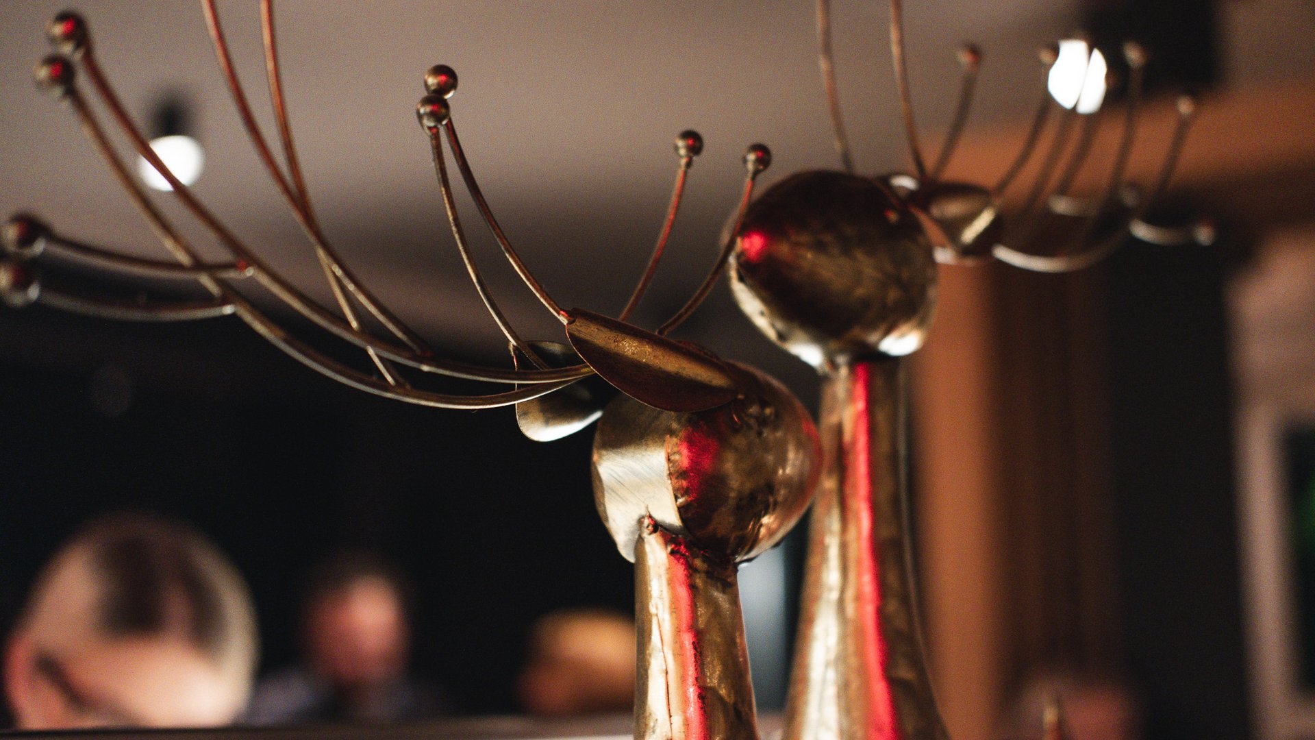 Hirschenblobb: Our bar Metal deer sculpture with long thin antlers against a blurred background