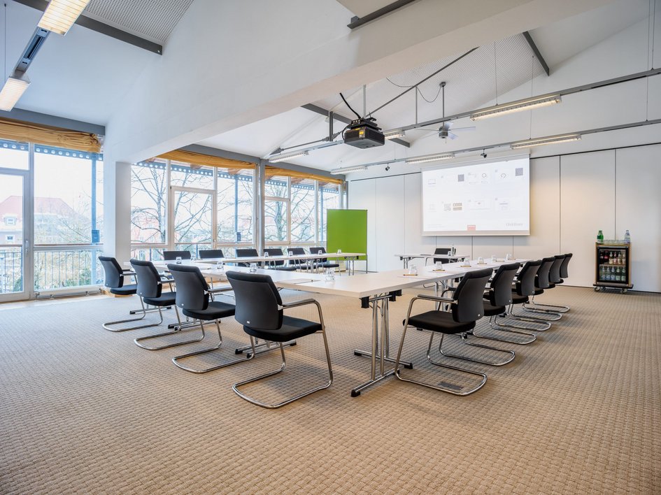 Looking for somewhere for conferences in Bavaria? Bright large conference room with U-shaped tables and projected presentation