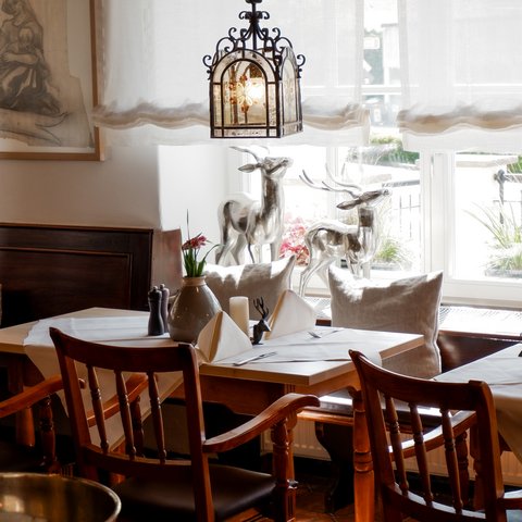 Gasthof Parsberg: Ein Gruß an den guten Geschmack Gemütliches Restaurant mit Holzstühlen, Tischdekoration und Fensterdeko mit Hirschfiguren