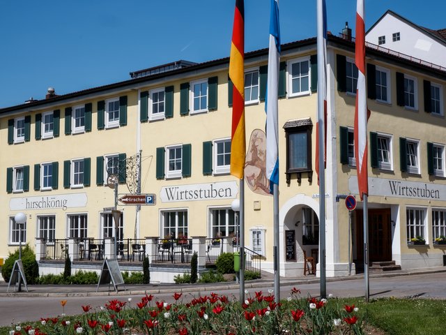 Romantik Hotel Hirschen: Bildergalerie Gelbes Gebäude mit weißem Schild 'Wirtsstuben' und Blumenbeet im Vordergrund