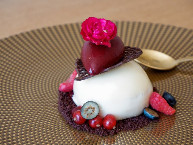 Romantik Hotel Hirschen: Bildergalerie Elegantes Dessert mit weißer Creme, Schokolade, Beeren und roter Blüte
