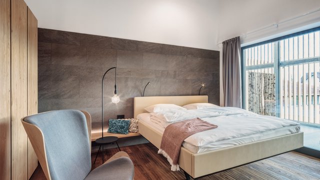Entspannung in der Oberpfalz: Garten & Ruheräume Modernes Schlafzimmer mit großen Fenstern, einem Bett und einem grauen Sessel