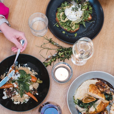Guesthouse in Parsberg: A salute to great taste Three plates with different food and hands holding cutlery on a wooden table