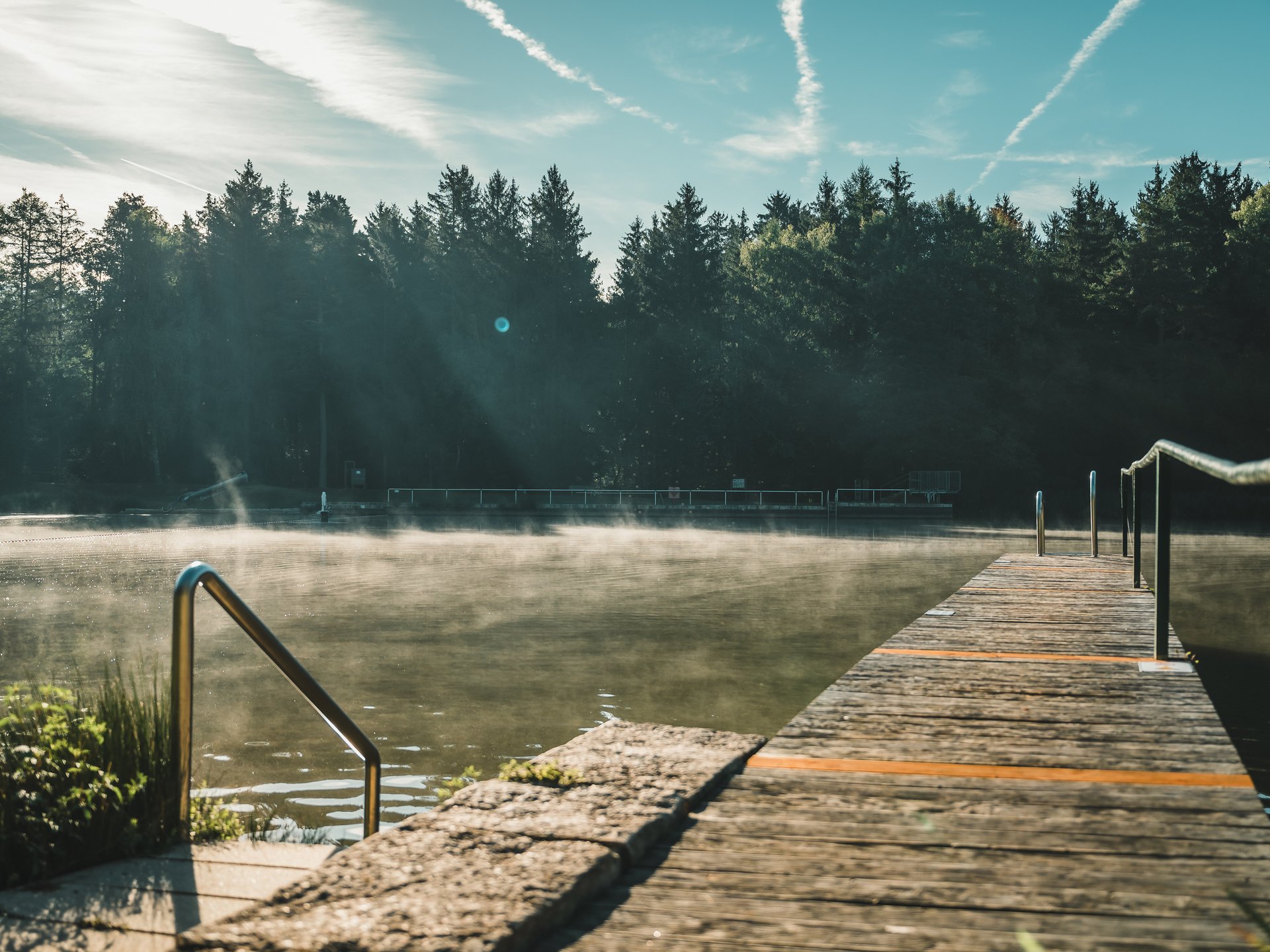 Badeseen Steg am nebligen See mit Wald im Hintergrund bei Sonnenaufgang