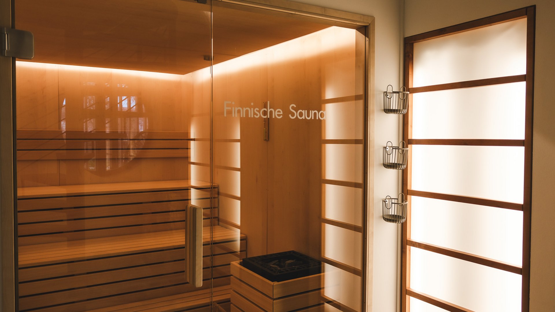Wellnesshotel in der Oberpfalz: schwitzen & schwimmen Innenansicht einer finnischen Sauna mit Holzbänken und beleuchtetem Glas