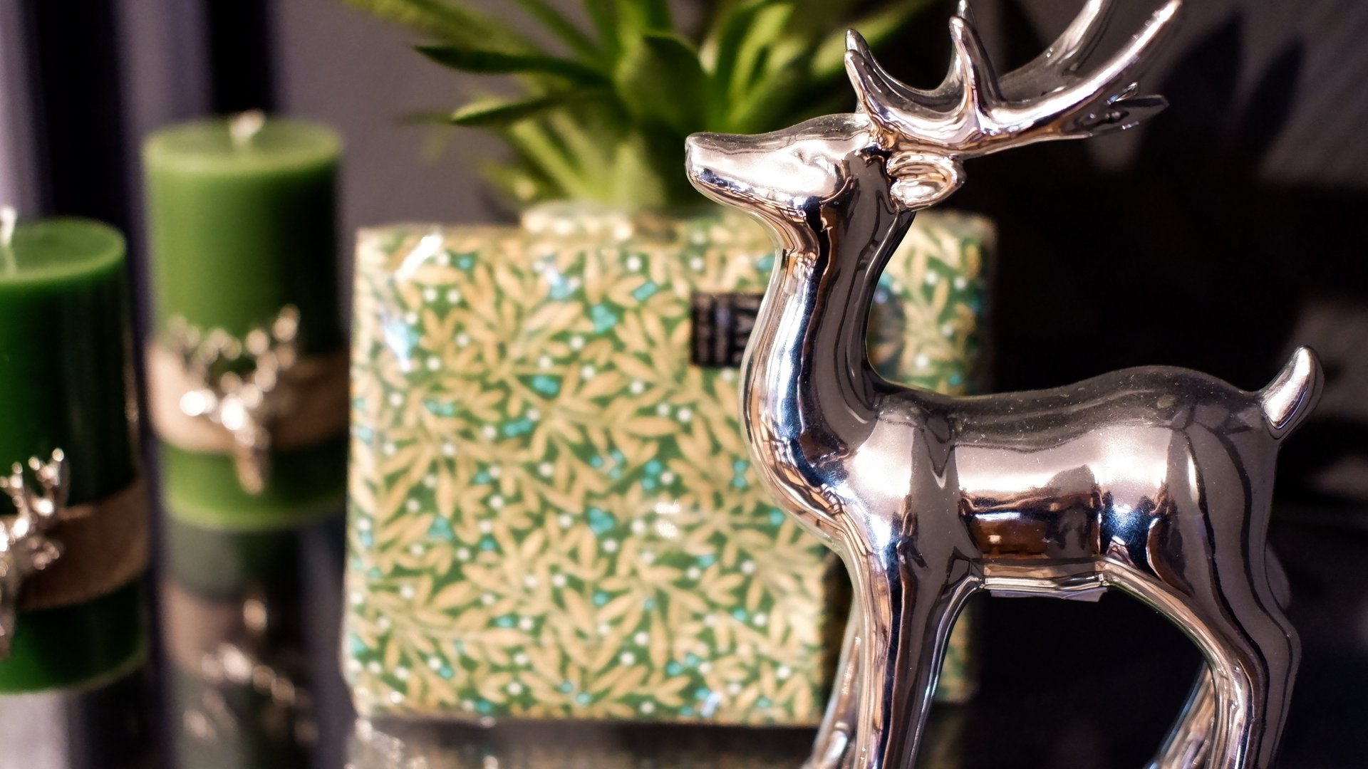 Eco-friendly hotel in Germany with Hirschenmanufaktur Silver deer figure beside green candles and plant on glass surface