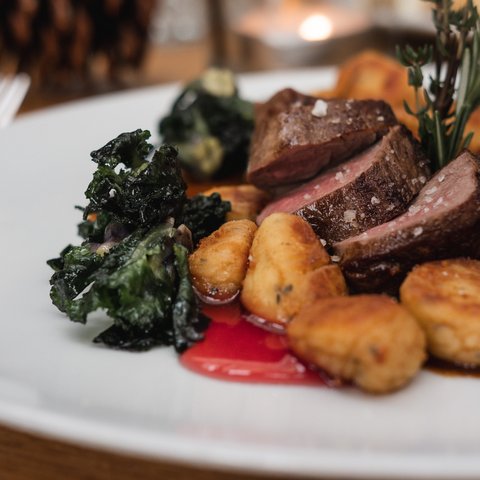 Gasthof Parsberg: Ein Gruß an den guten Geschmack Gebackene Kartoffelgnocchi mit Rindersteak und grünem Gemüse auf weißem Teller