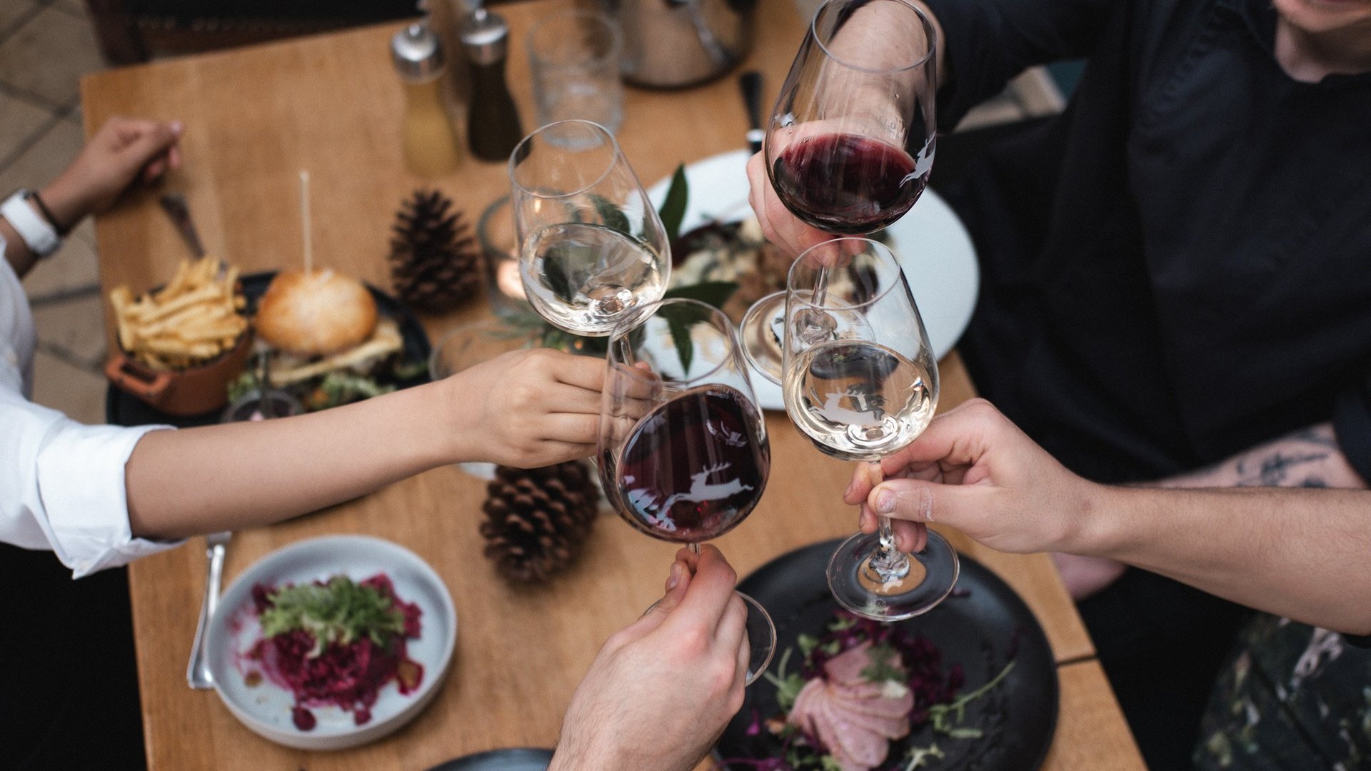 Christmas menus 2023 People toasting with red and white wine glasses over a set dining table