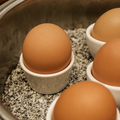 Romantik Hotel Hirschen: Frühstück Braune Eier in weißen Eiern-bechern über Steinen in einem Topf