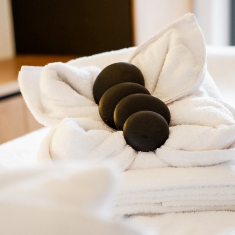Tageswellness in der Oberpfalz Weiße Handtücher mit schwarzen Massage-Steinen darauf gefaltet