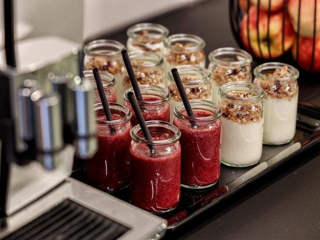 Romantik Hotel Hirschen: Bildergalerie Gläser mit rotem Smoothie und Joghurt mit Müsli auf einem Tablett