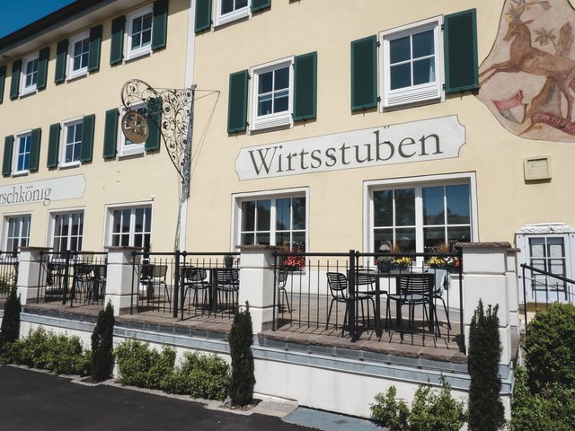 Romantik Hotel Hirschen: Bildergalerie Außenansicht eines Gebäudes mit Terrasse und dem Schriftzug Wirtstuben