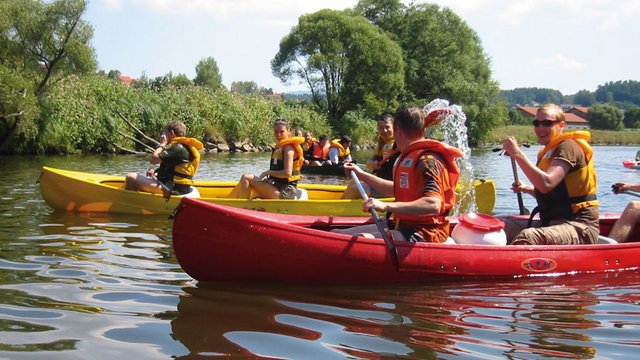 Looking for somewhere for conferences in Bavaria? Group of people kayaking on calm river wearing life jackets on a sunny day