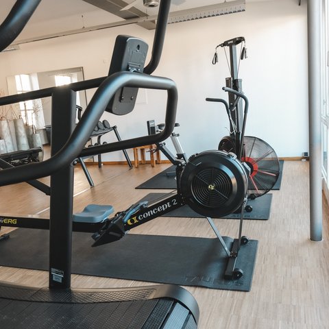 Fitnessraum Gym room with treadmill and rowing machines on wooden floor