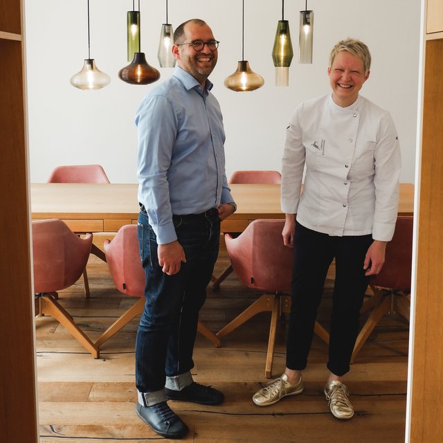 Restaurant in Parsberg: Gourmet genießen Mann und Frau in Kochjacke stehen lachend in modernem Esszimmer
