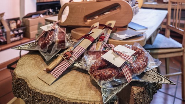 Romantik Hotel Hirschen: Blog Verschiedene eingepackte Würste und Messer auf Holztisch in einem rustikalen Laden