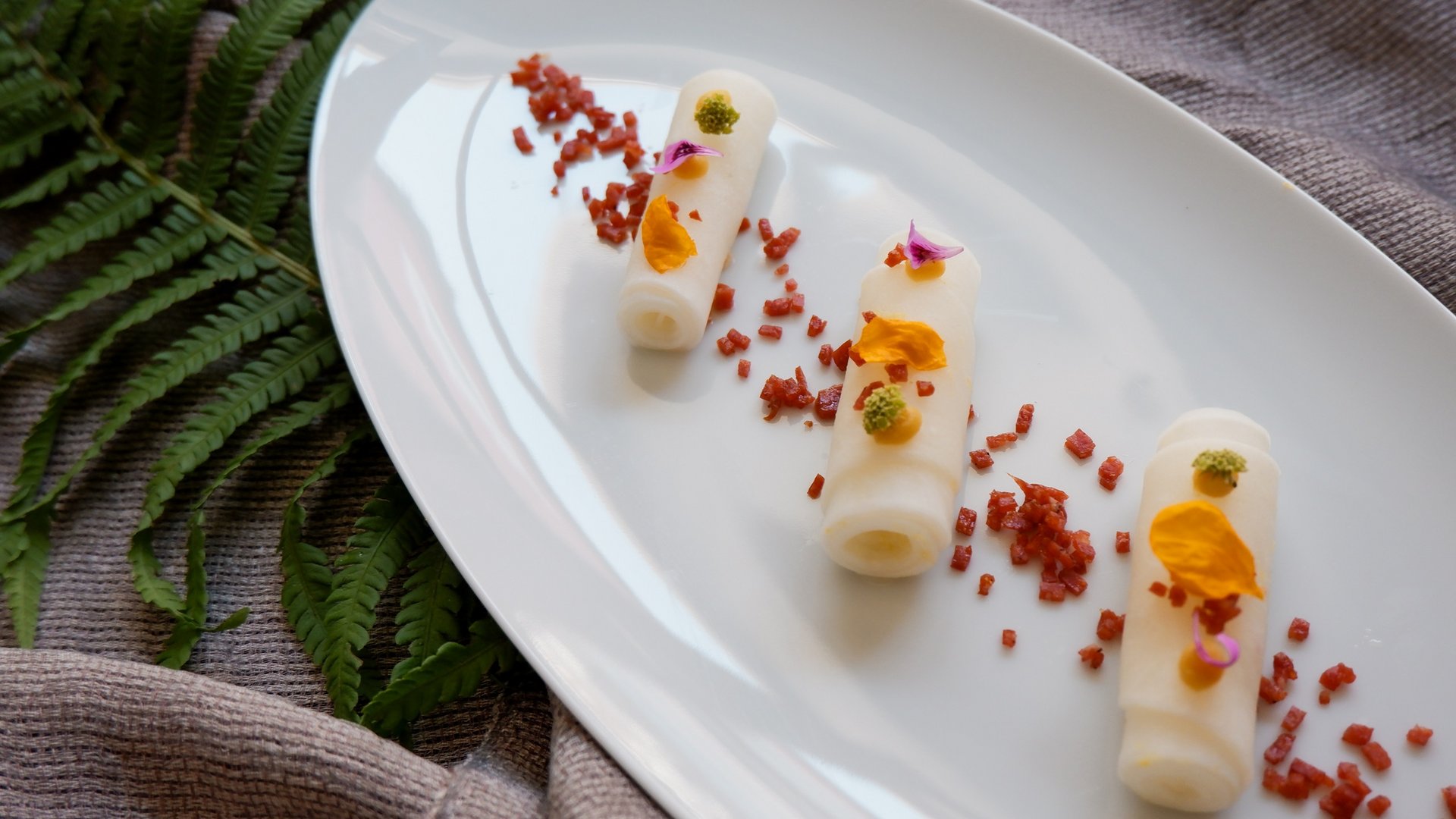 Romantik Hotel Hirschen: cuisine Three rolled fine appetizers with colorful petals and spices on a white plate