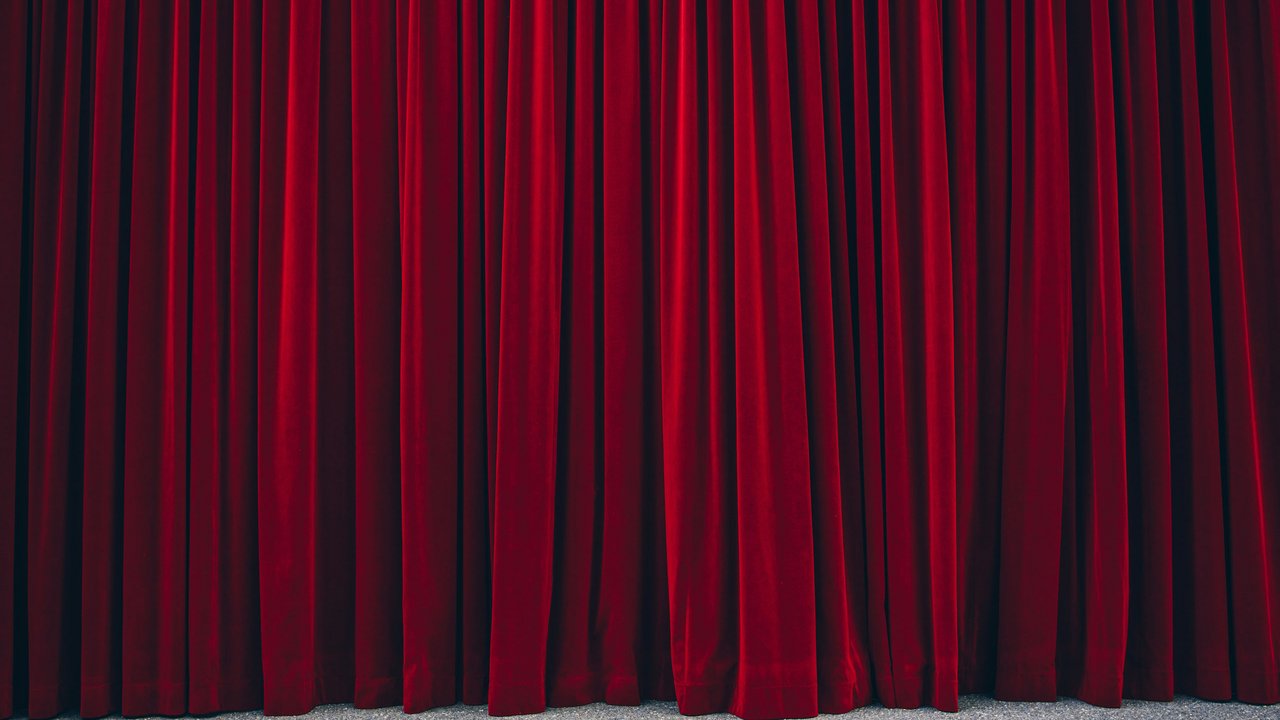Geschlossene rote Theatervorhänge auf einem grauen Boden
