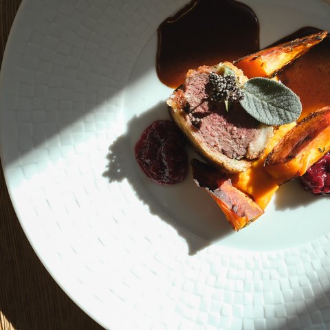 Fine Dining & Gourmet Cuisine in the Upper Palatinate Sliced meat with roasted vegetables, sauce and sage on a white plate