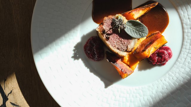 Gasthof & Restaurant in Parsberg mit regionaler Küche Aufgeschnittenes Fleisch mit geröstetem Gemüse, Sauce und Salbei auf einem weißen Teller
